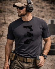 Man at gun range wearing a graphite black t-shirt with black images of a glock, paper hand sign, and scissors hand sign