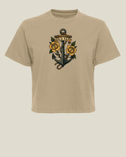 A beige short-sleeve crewneck tboxy tee featuring a traditional tattoo-style graphic of an anchor surrounded by yellow roses and the words 'HOLD FAST' on the chest, set against a solid light beige background.