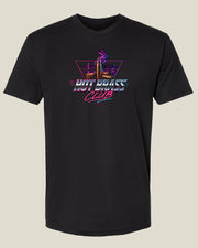 A black short-sleeve crewneck t-shirt featuring a colorful retro neon-style graphic on the chest that reads 'HOT BRASS CLUB' with a stylized neon 80s inspired illustration of smoking brass shell casings in front of a city ckyline, shown against a solid light beige background.